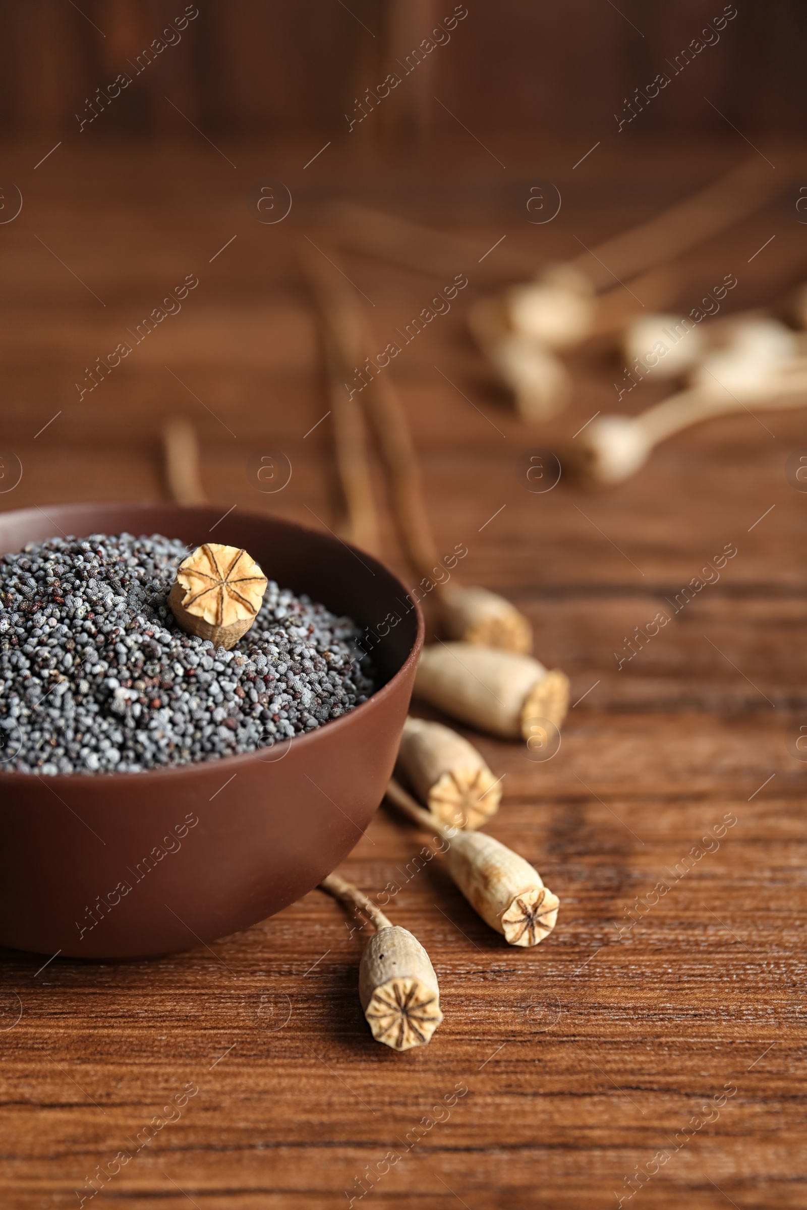 Photo of Bowl with poppy seeds on wooden table