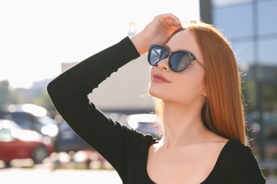 Beautiful woman in sunglasses on city street, space for text