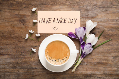 Photo of Morning coffee, flowers and card with HAVE A NICE DAY wish on wooden table, flat lay