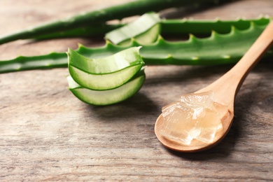 Photo of Spoon with aloe vera gel on wooden background