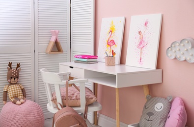 Photo of Stationery and pictures on white table in children's room. Interior design