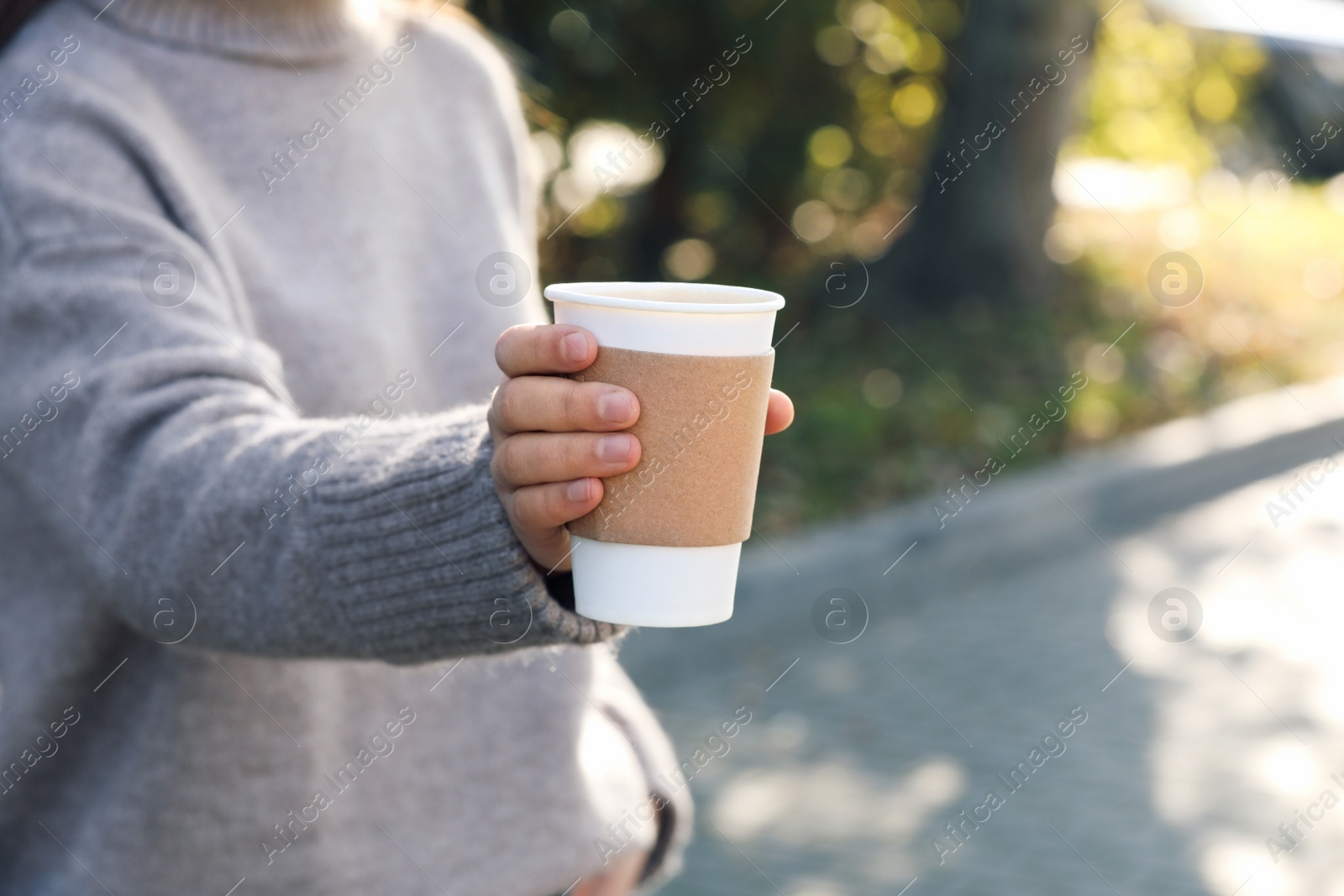 Photo of Coffee to go. Woman holding takeaway cardboard cup on city street, closeup. Space for text