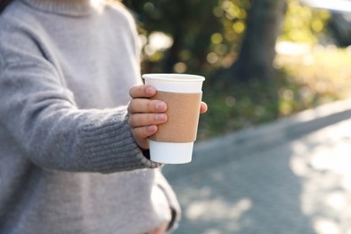 Coffee to go. Woman holding takeaway cardboard cup on city street, closeup. Space for text