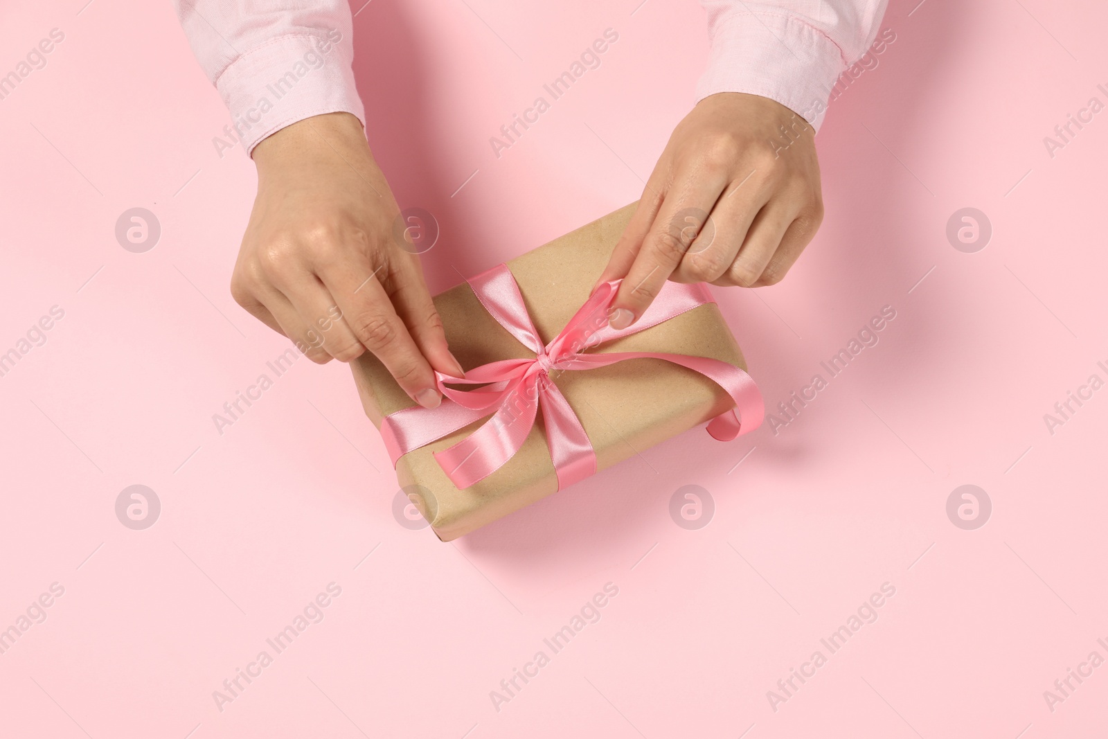 Photo of Woman with gift box on pink background, top view