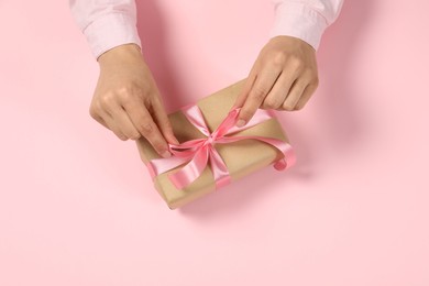 Woman with gift box on pink background, top view