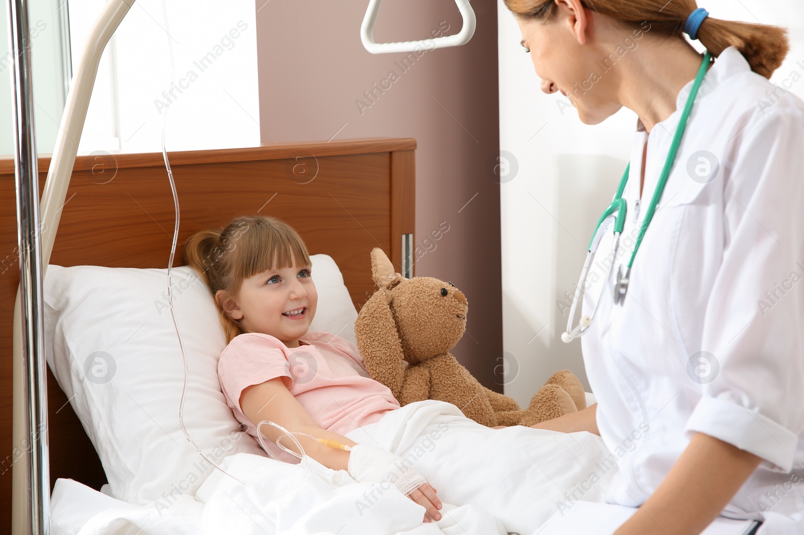 Photo of Doctor visiting little child with intravenous drip in hospital