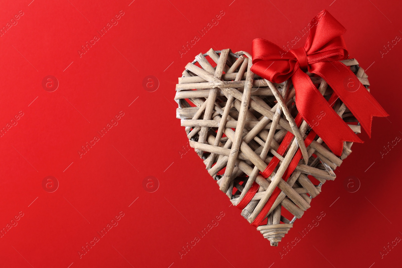 Photo of Wooden heart with bow on red background, top view. Space for text