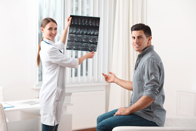 Photo of Orthopedist showing X-ray picture to patient in clinic