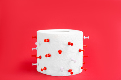 Photo of Roll of toilet paper with pins on red background. Hemorrhoid problems