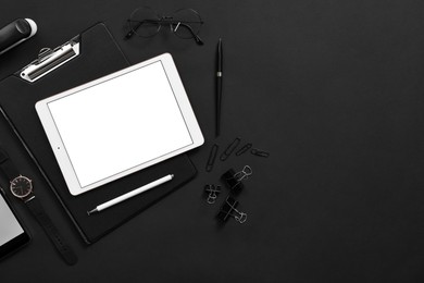 Modern tablet, stationery, wristwatch and glasses on black background, flat lay. Space for text