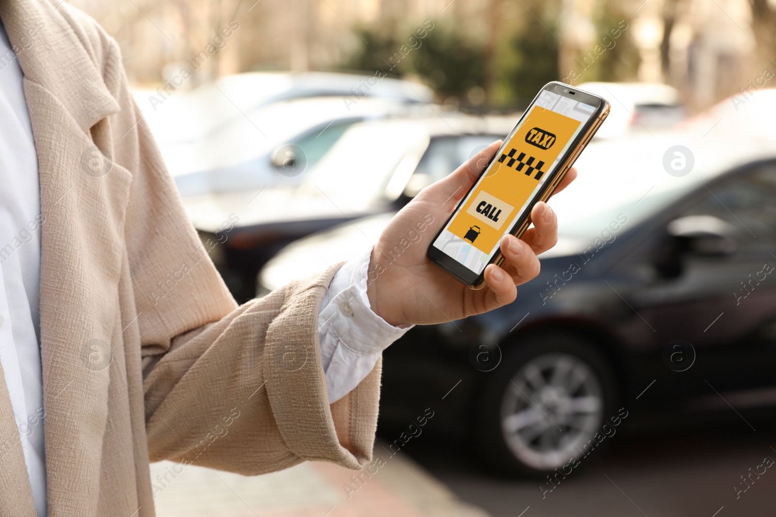 Photo of Woman ordering taxi with smartphone on city street, closeup