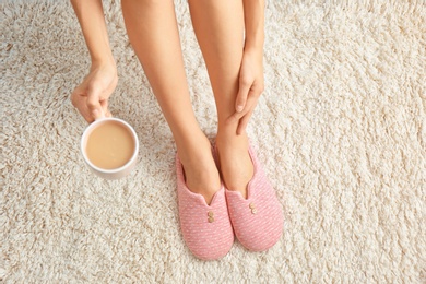 Photo of Woman with cup of coffee on carpet, closeup. Floor heating