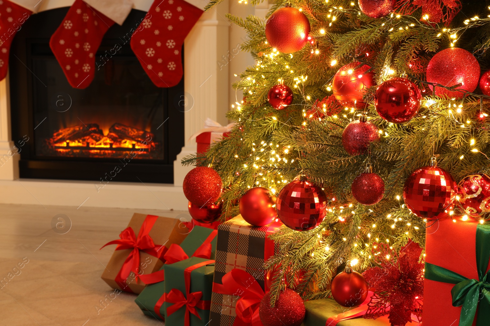 Photo of Many gift boxes under decorated Christmas tree and fireplace indoors