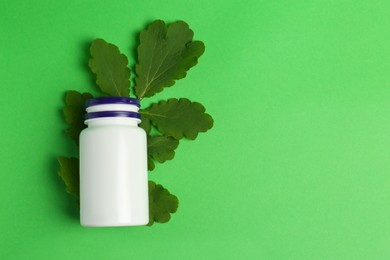 Photo of Medicine bottle and leaves on green background, top view. Space for text