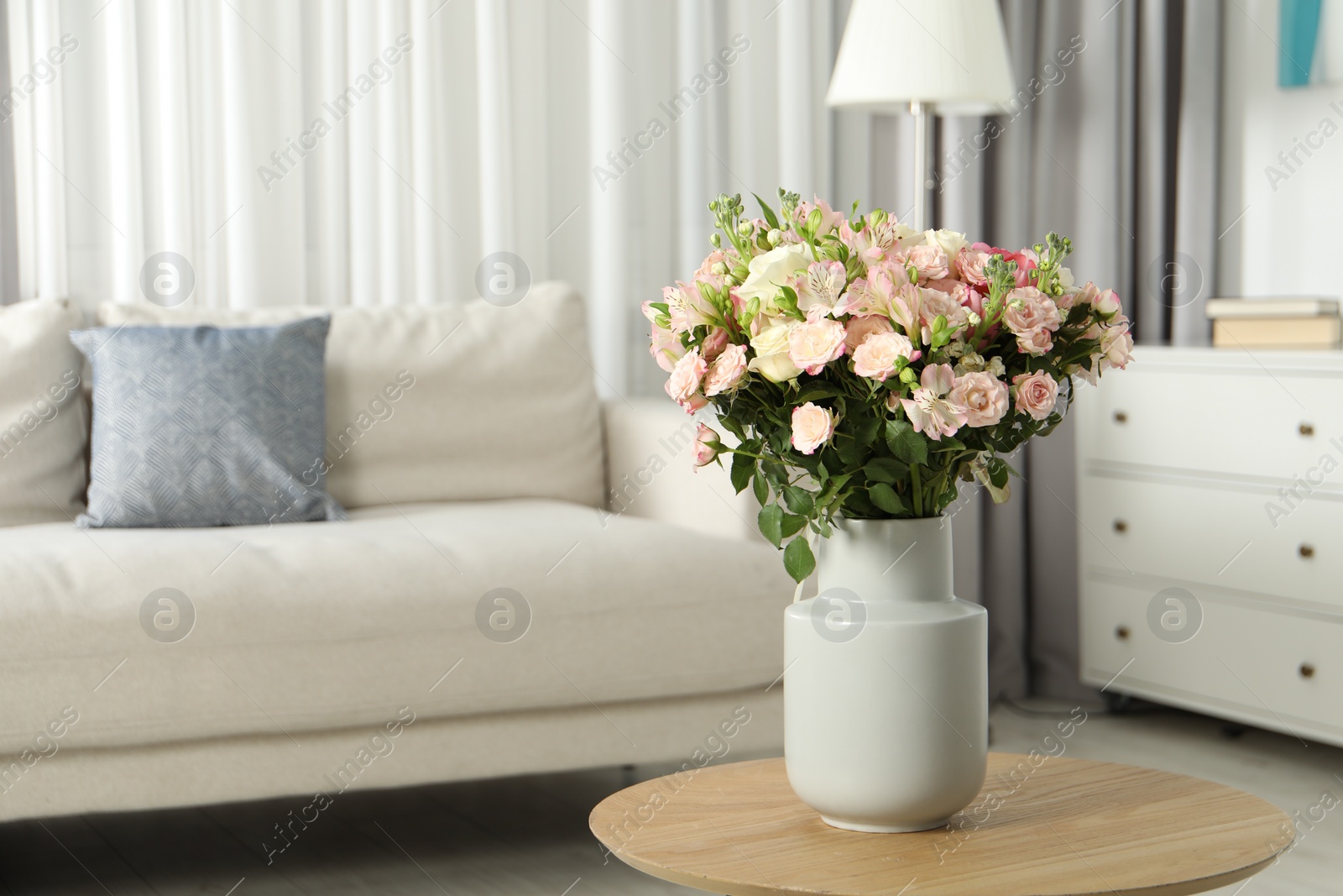 Photo of Beautiful bouquet of fresh flowers in vase on wooden coffee table indoors, space for text