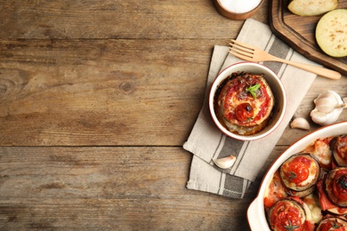 Photo of Baked eggplant with tomatoes, cheese and basil served on wooden table, flat lay. Space for text