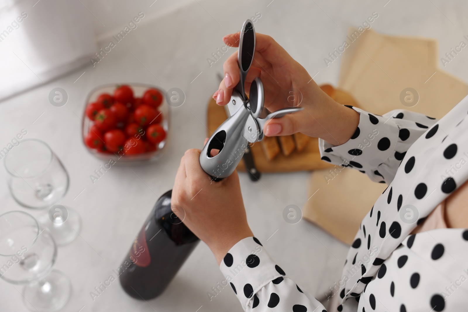 Photo of Romantic dinner. Woman opening wine bottle with corkscrew at table, above view