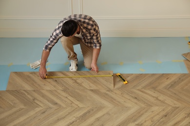 Professional worker installing new parquet flooring indoors, above view