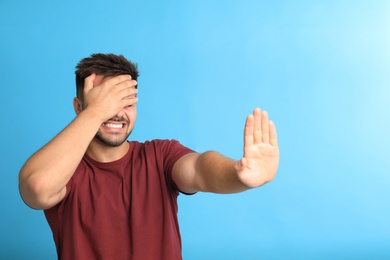 Young man being blinded on blue background