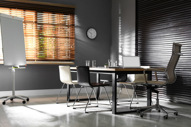 Photo of Stylish office interior with wooden table and flipchart