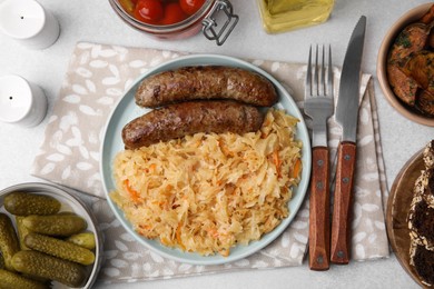 Photo of Plate with sauerkraut and sausages served on light grey table, flat lay