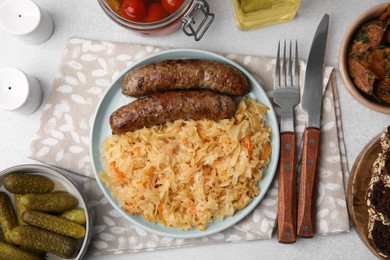 Plate with sauerkraut and sausages served on light grey table, flat lay