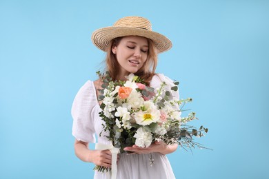 Photo of Beautiful woman in straw hat with bouquet of flowers on light blue background