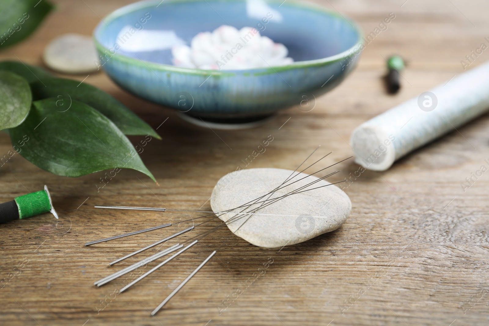 Photo of Stone with acupuncture needles on wooden table