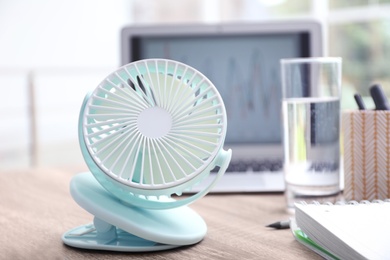 Photo of Modern portable fan on wooden table in office. Summer heat