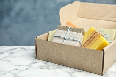 Cardboard box with different handmade soap bars on table. Space for text