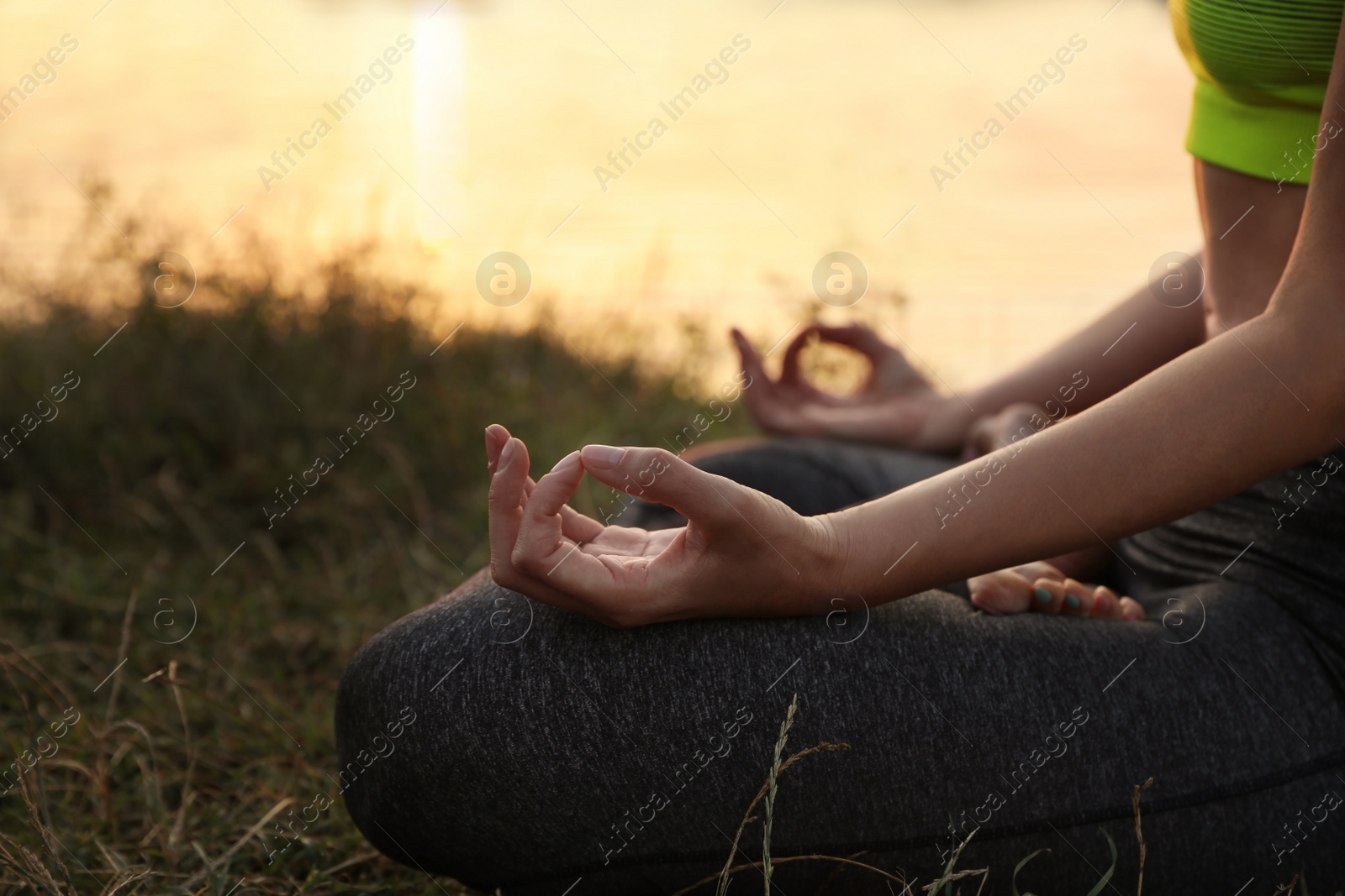 Photo of Woman meditating near river at sunset, closeup. Space for text