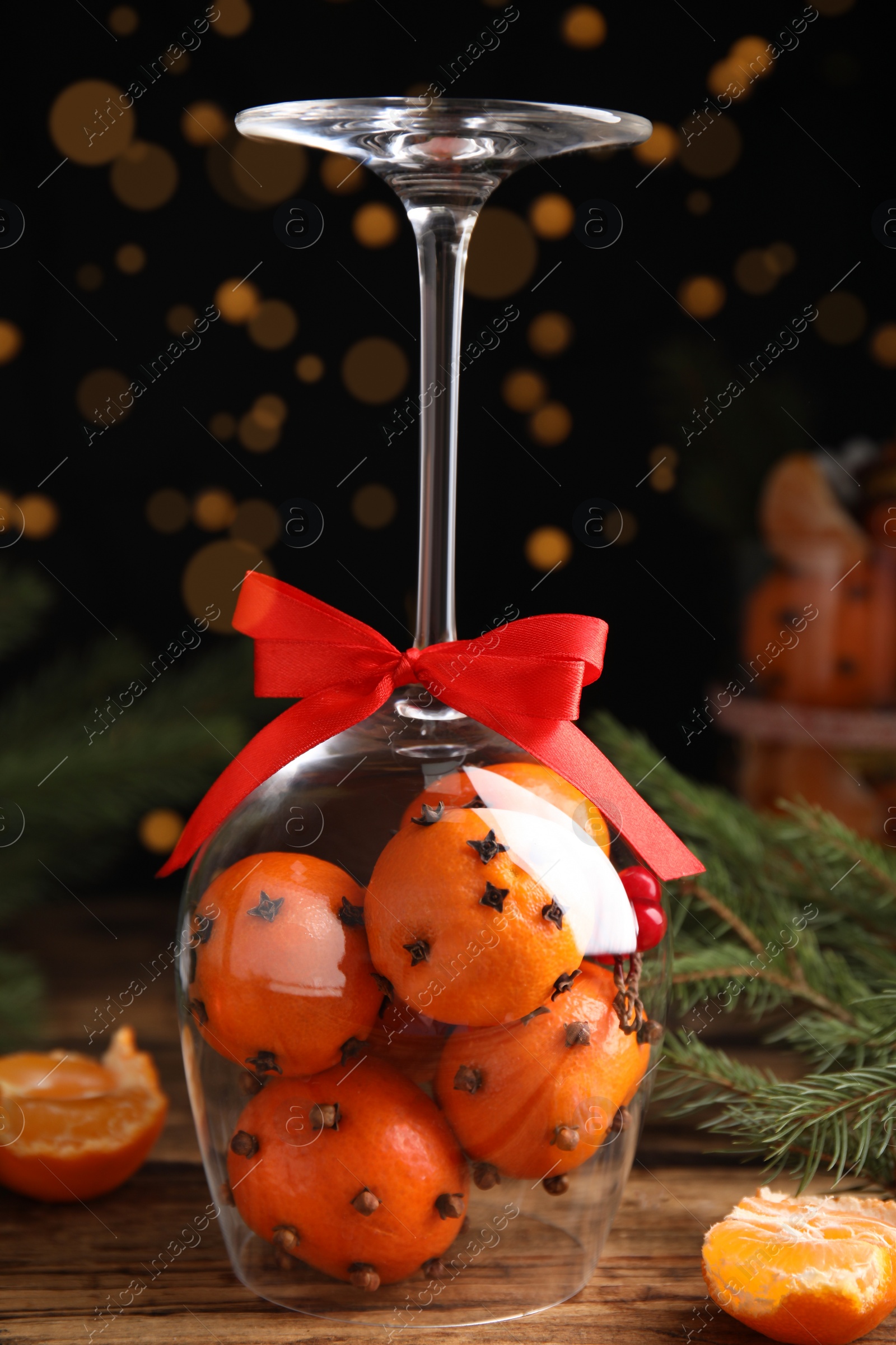 Photo of Christmas composition with tangerine pomander balls in wineglass on wooden table