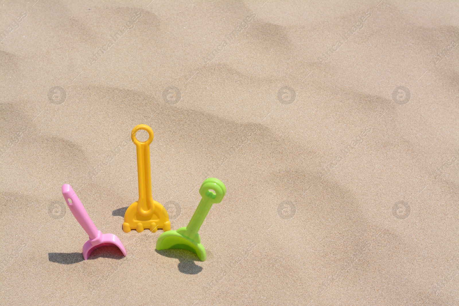 Photo of Set of colorful beach toys on sand, space for text