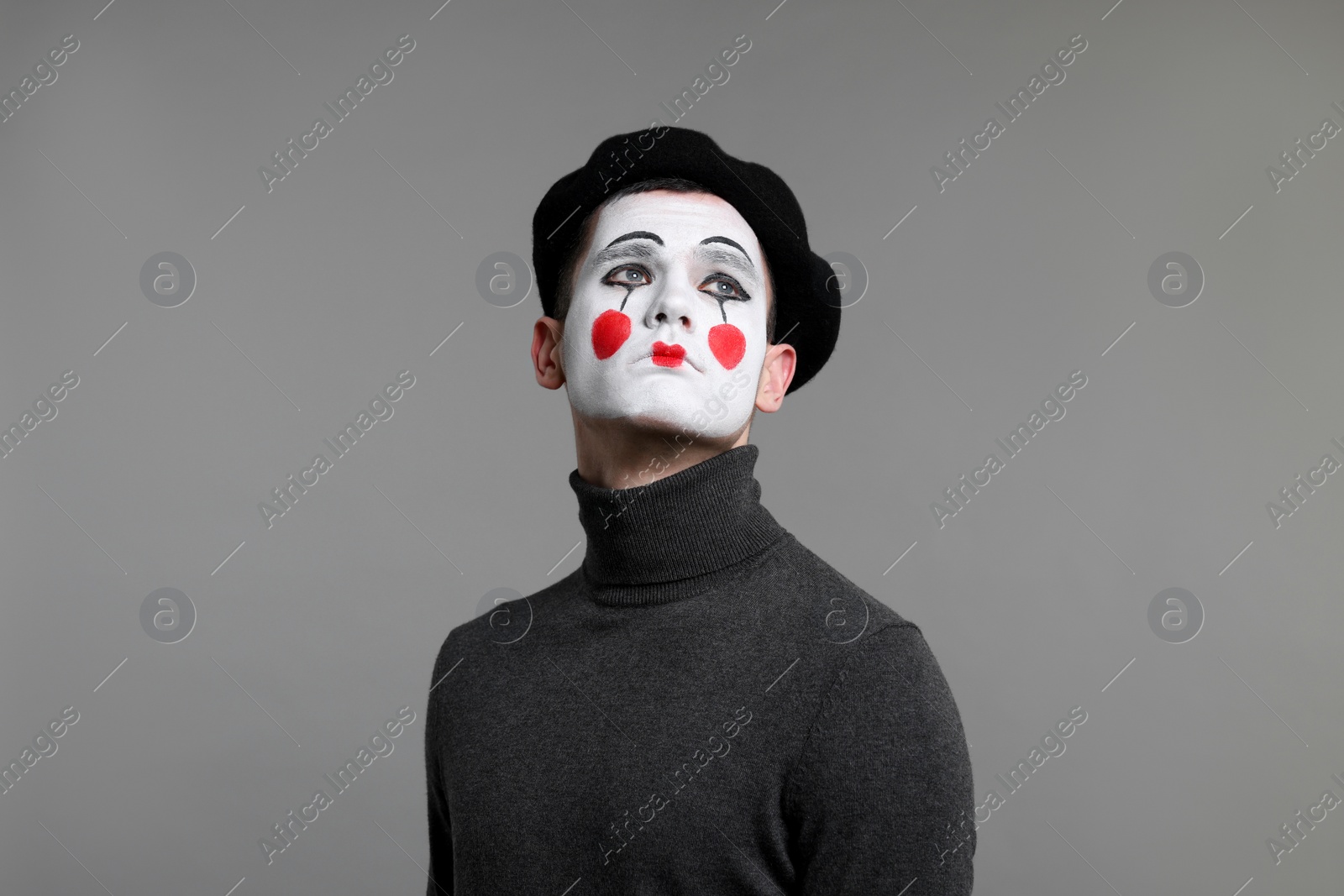 Photo of Portrait of mime artist in beret on grey background