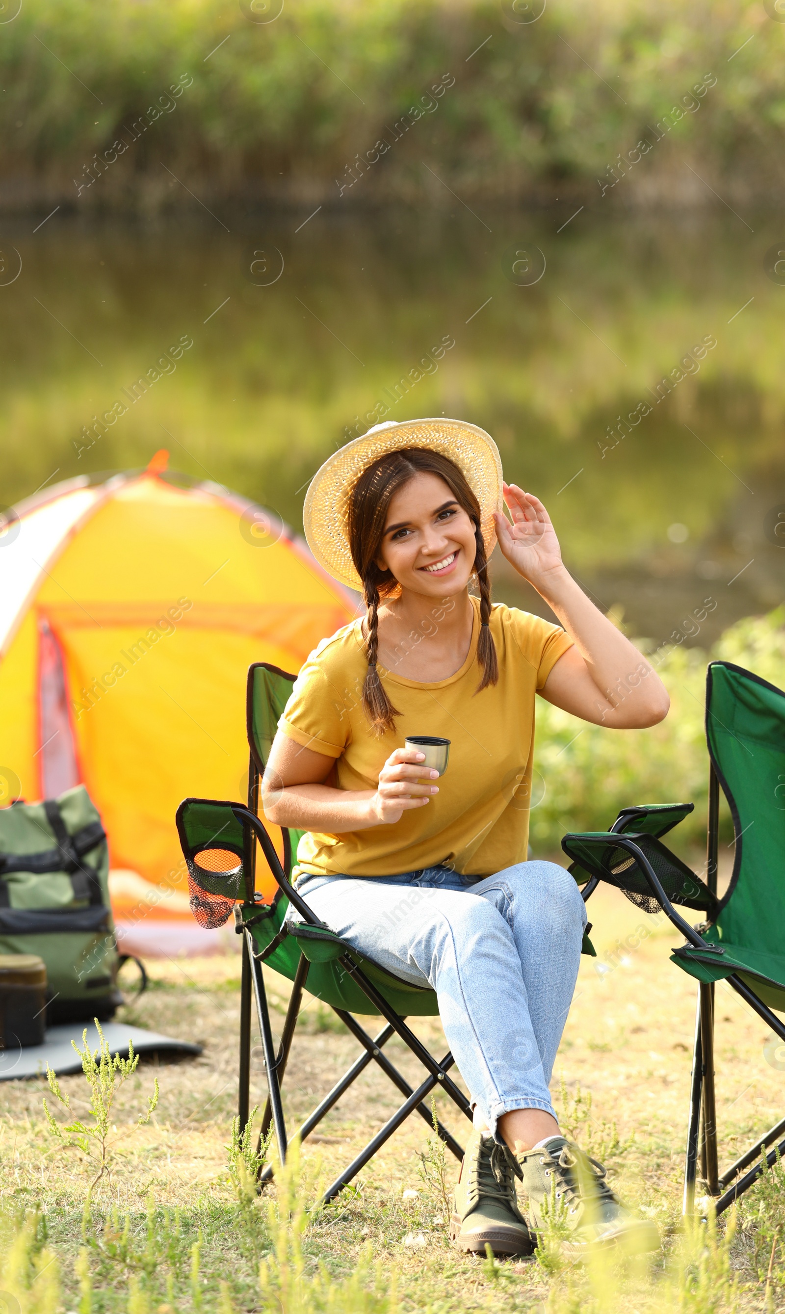 Photo of Young woman with hot drink resting outdoors. Camping vacation