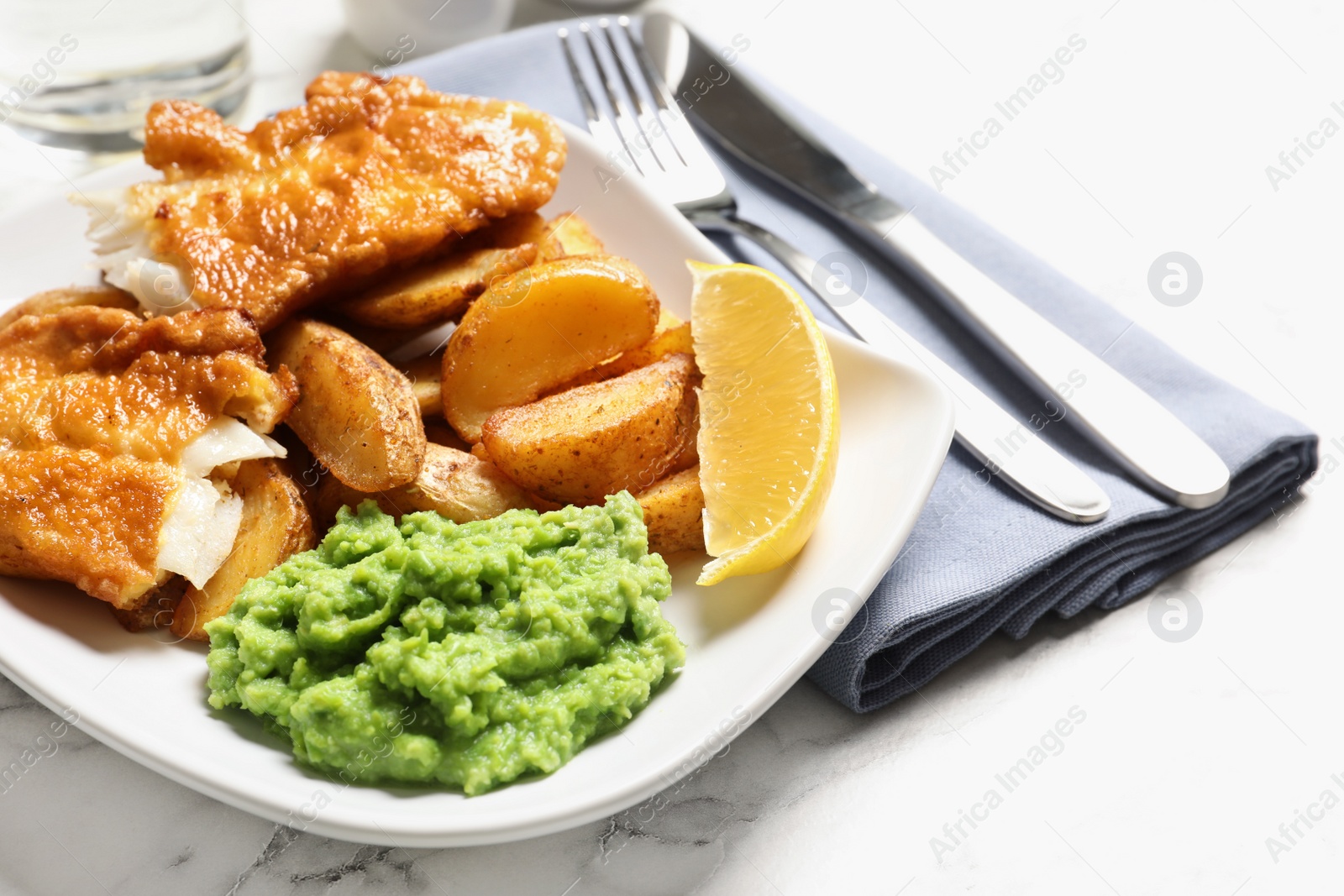 Photo of Plate with British traditional fish and potato chips on marble table