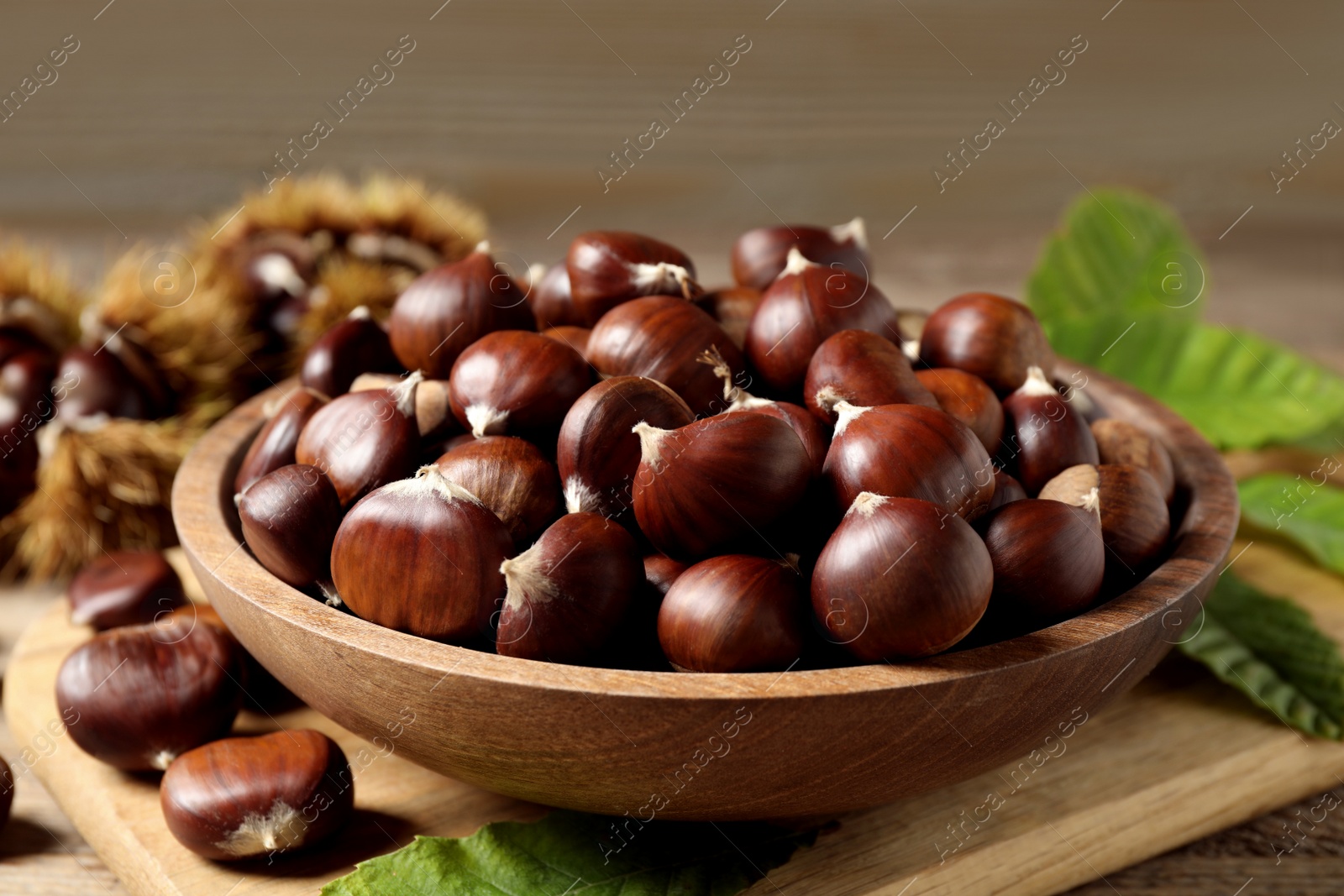 Photo of Fresh sweet edible chestnuts on wooden board, closeup