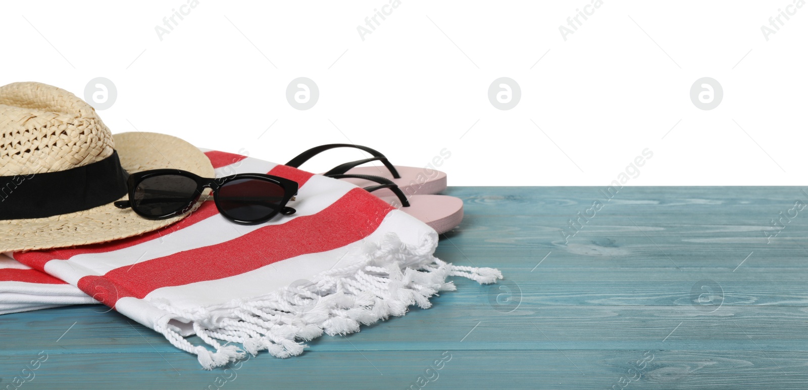 Photo of Beach towel, straw hat, flip flops and sunglasses on light blue wooden surface against white background. Space for text