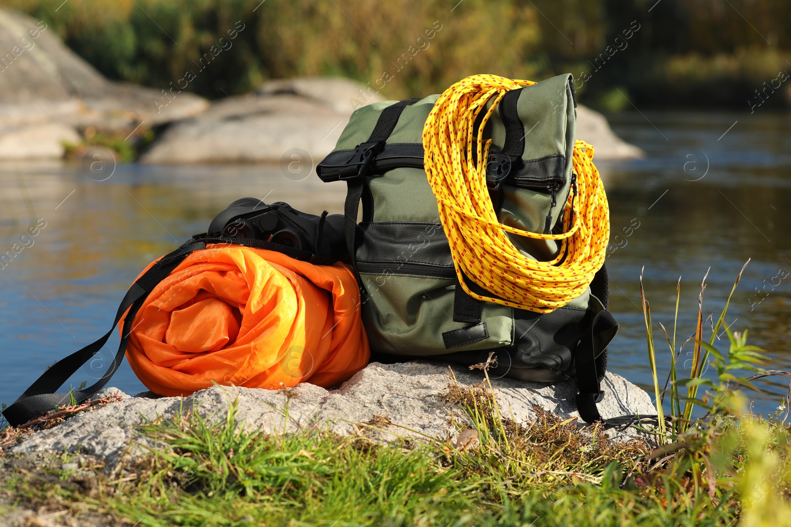 Photo of Set of camping equipment with sleeping bag on rock outdoors