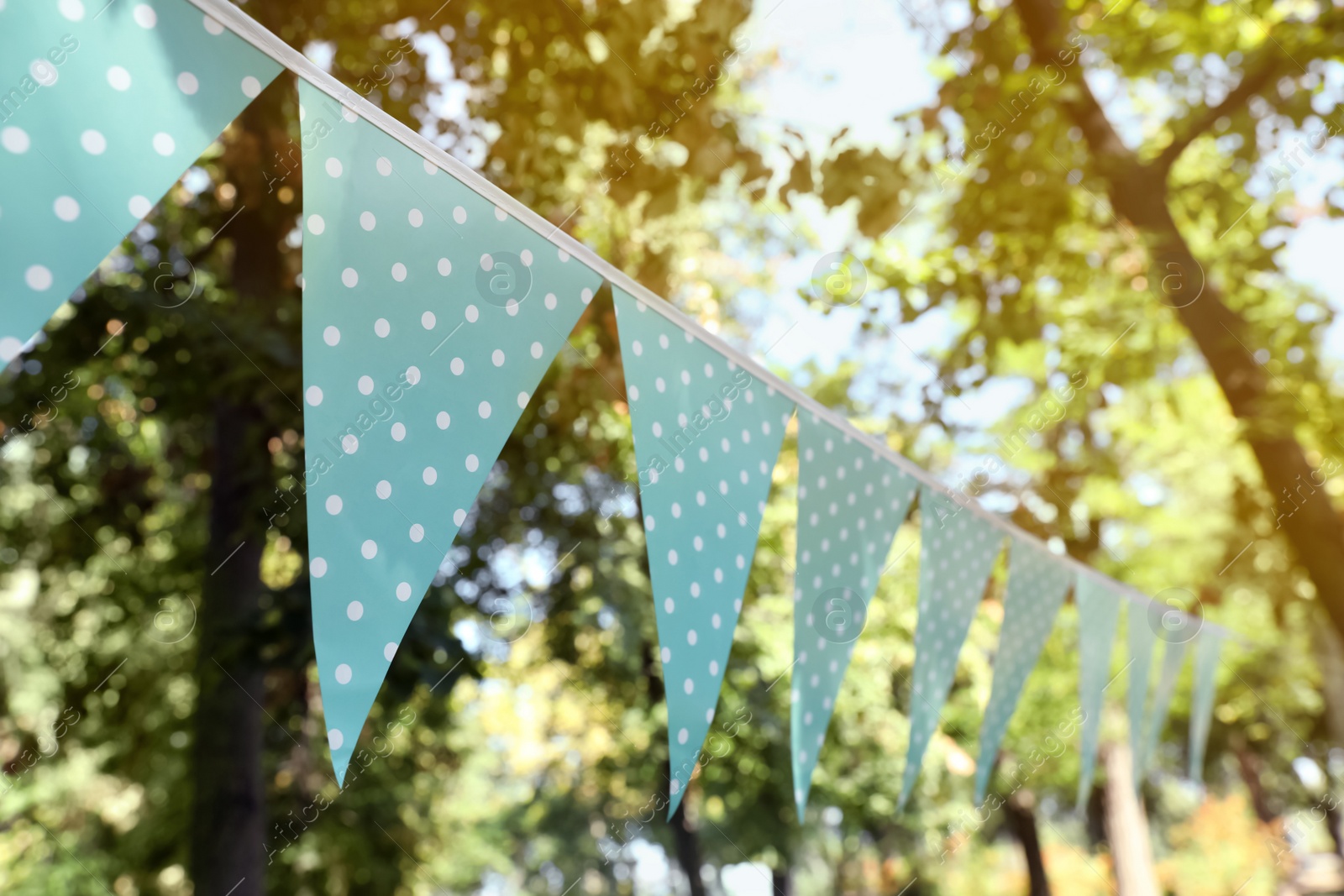 Photo of Light blue bunting flags in park. Party decor