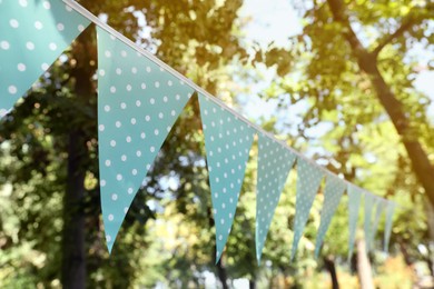 Light blue bunting flags in park. Party decor