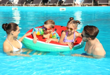 Photo of Young family with little children in swimming pool on sunny day