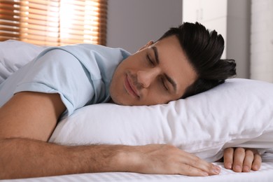 Photo of Man sleeping in comfortable bed with white linens