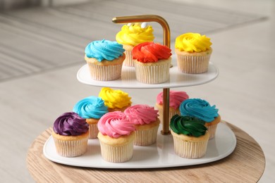 Photo of Delicious cupcakes with bright cream on wooden table indoors, closeup