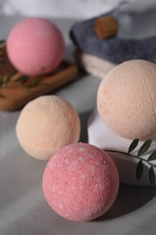 Beautiful aromatic bath bombs and green twig on grey table