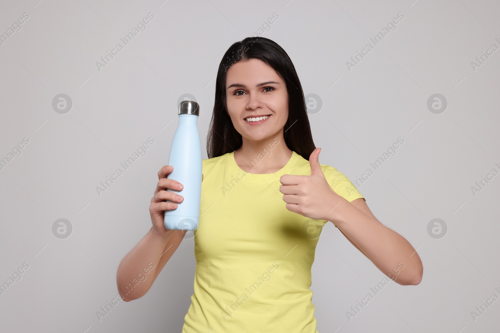 Photo of Young woman with thermo bottle on light grey background