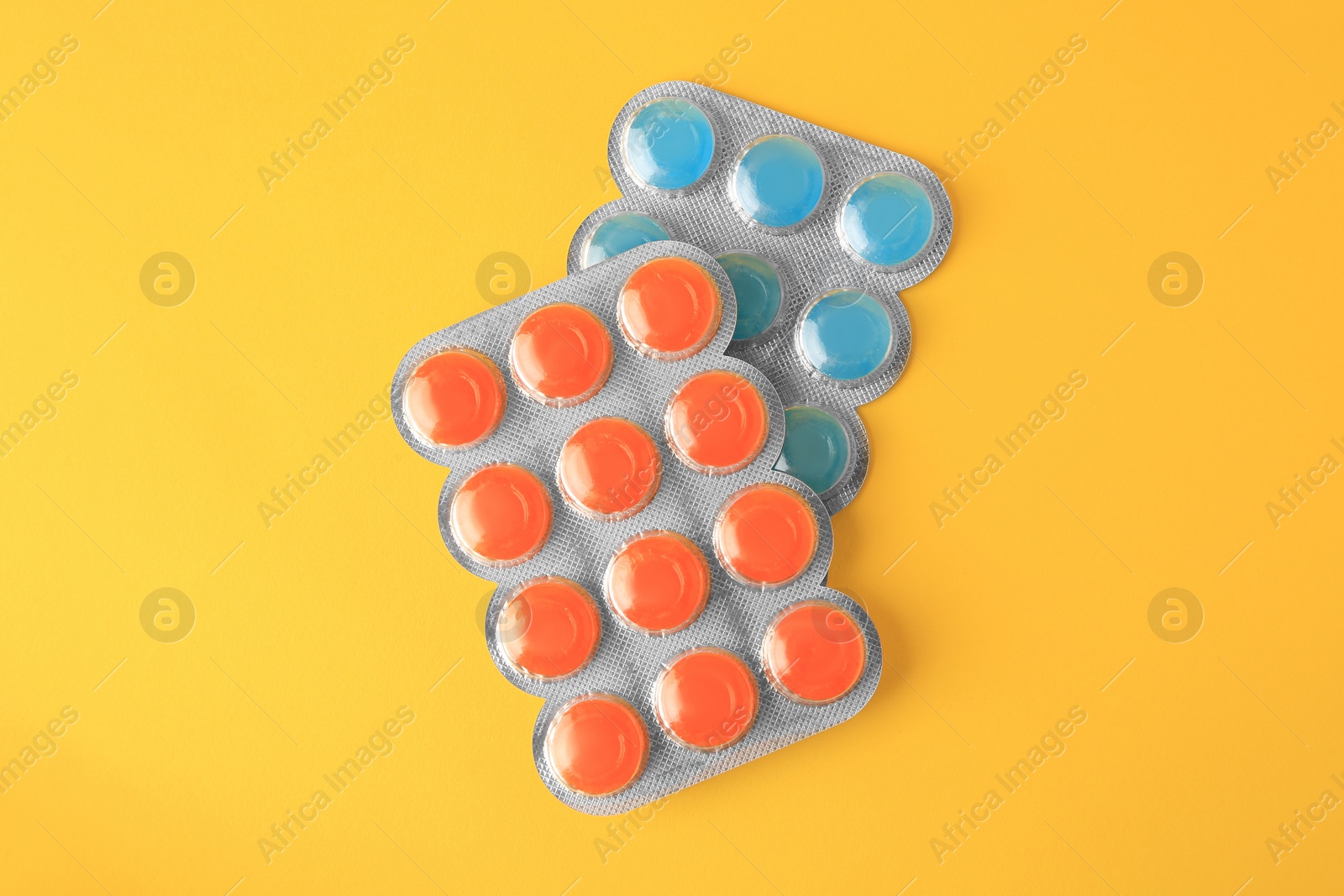 Photo of Blisters with cough drops on yellow background, flat lay