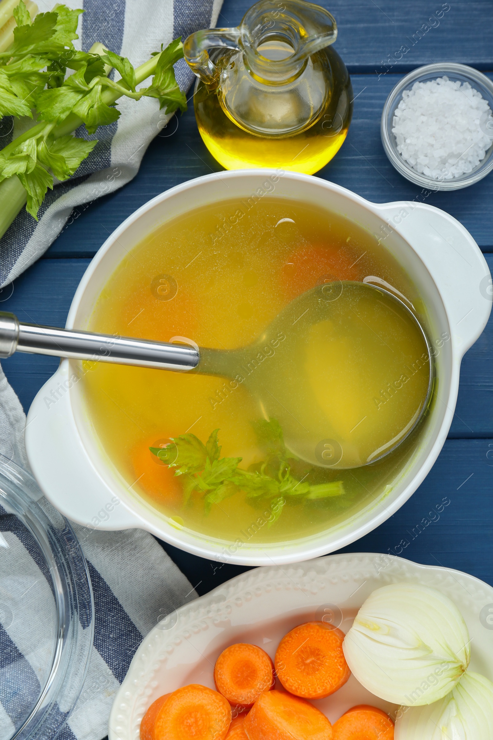 Photo of Delicious chicken bouillon and ingredients on blue wooden table, flat lay