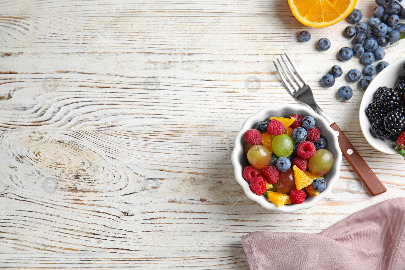 Photo of Fresh tasty fruit salad on white wooden table, flat lay. Space for text