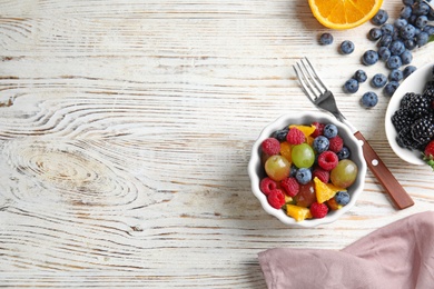 Photo of Fresh tasty fruit salad on white wooden table, flat lay. Space for text